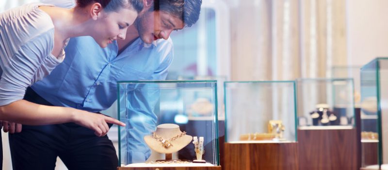 What factors influence your diamond buying process? Couple buying jewellery pointing at necklace in display case