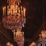 image of opulent chandeliers along a hallway with dark background